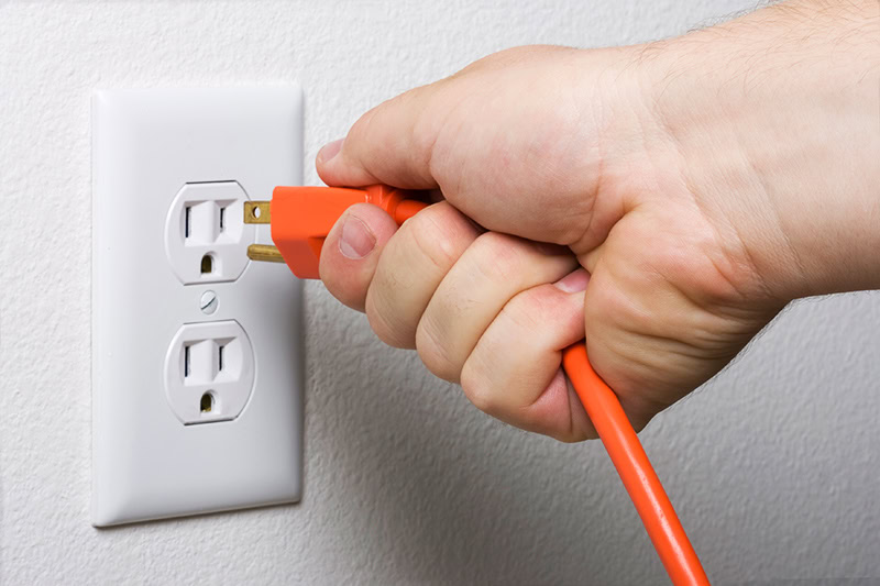 Plugging in a cord to an outlet.