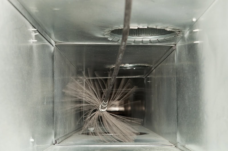 Top view of an air duct being cleaned with a brush.