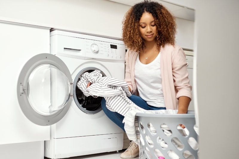 Dryer Vent Cleaning. Shot of a young attractive woman doing laundry at home.